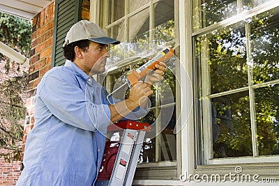 Calking on Home   Royalty Free Stock Photo  Man Caulking Window